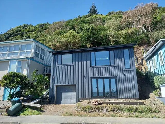 Finished re-roof and re-clad on a two-storey home under a blue sky
